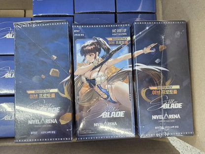 Three sealed Nivel Arena Stella Blade booster boxes stacked on top of other boxes inside a cardboard box. The box feature game artwork of a female character , eve with long brown hair against a dark blue background.